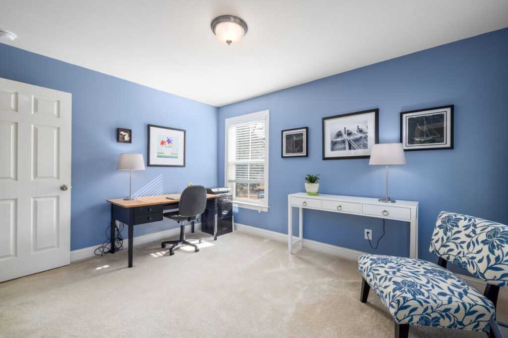 A stylish home office with blue walls, featuring a desk, chair, and laptop, ideal for productivity.