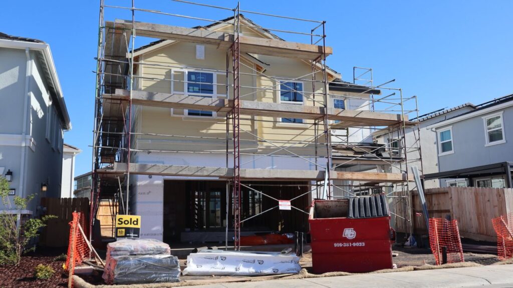 Under-construction house with scaffolding in Elk Grove, California, showing a sold sign in front.